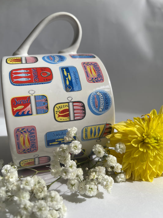 Decorative mug with colorful labels and a yellow flower on a white background