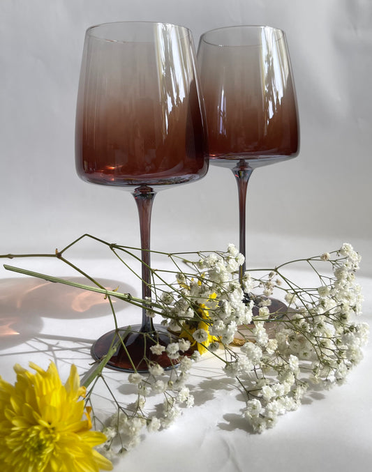 Two gradient wine glasses with flowers on a light background