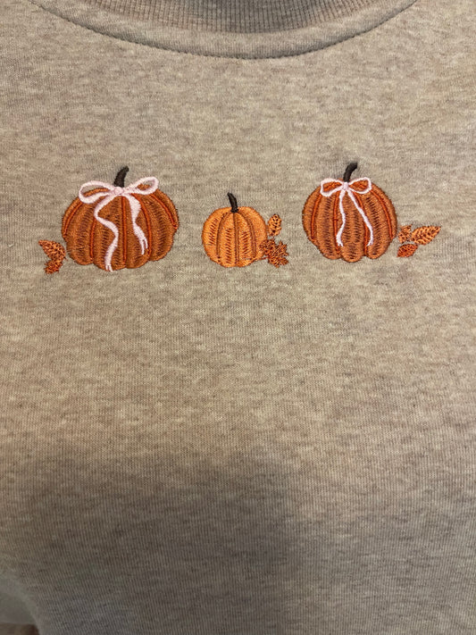 Gray sweatshirt with embroidered pumpkins and leaves on a plain background
