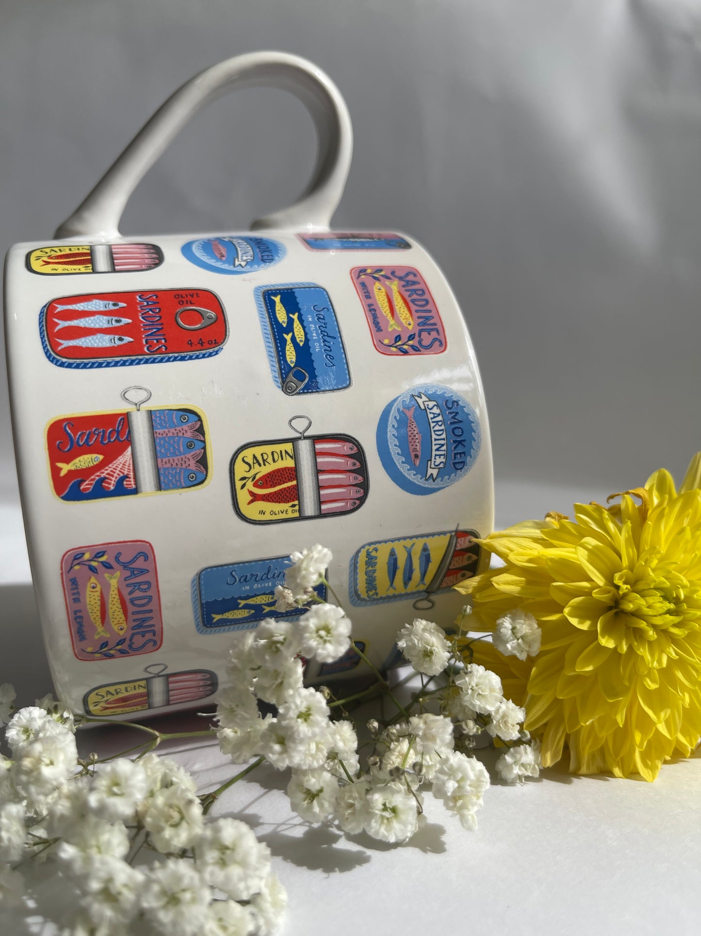Decorative mug with colorful labels and a yellow flower on a white background