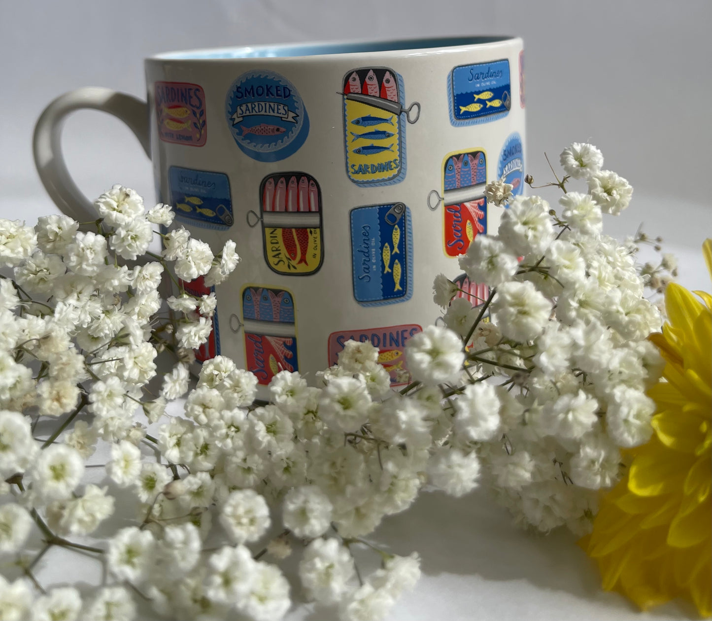 Mug with colorful designs surrounded by white flowers and a yellow flower