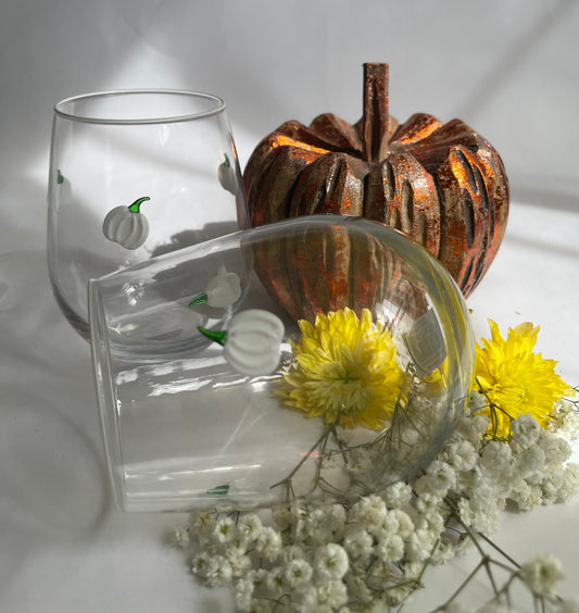 Clear glass with pumpkin design, rusty pumpkin decoration, and yellow flowers on a white background