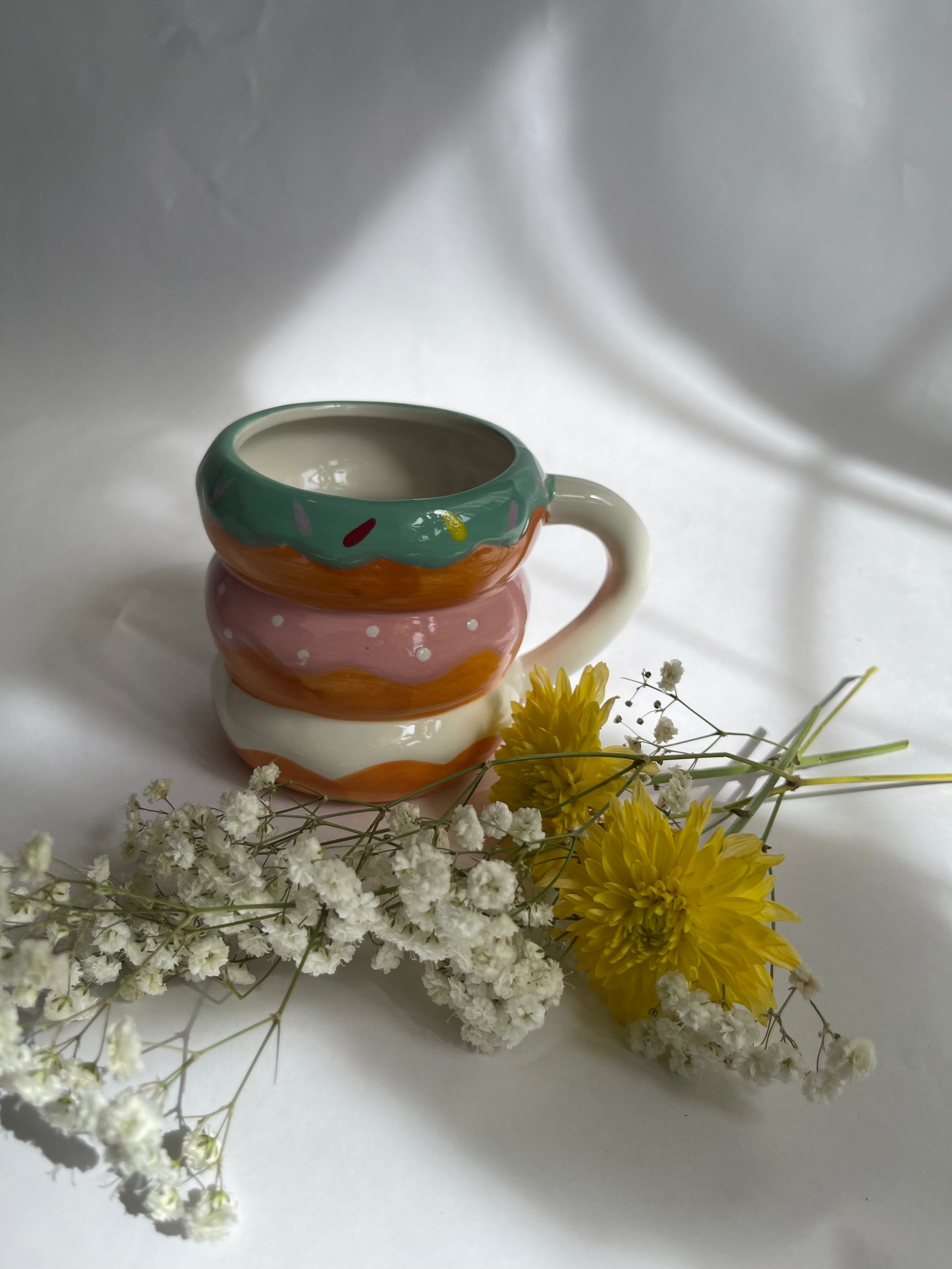 Colorful striped mug with flowers on a white surface