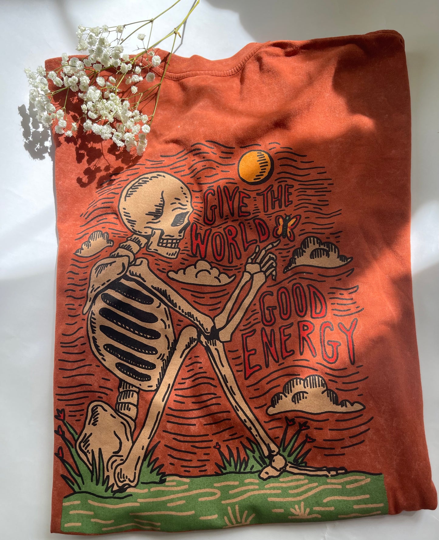 Orange tote bag with skeleton design and 'Give the World Good Energy' text on a white background