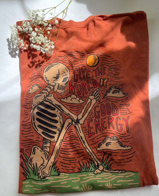 Orange tote bag with skeleton design and 'Give the World Good Energy' text on a white background